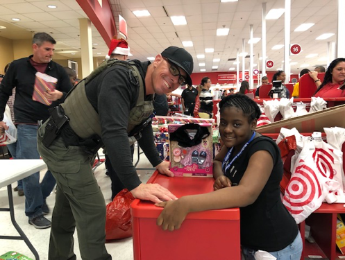 Police officer smiling with participating kid during Shop With A Cop event at Target