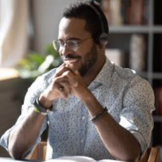 Gentleman seated with headphones on in a sunlit office.