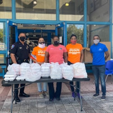 Lauderhill police officer, Commissioner Melissa P Dunn and three volunteers stand outside of the Boys and Girls club at a table with boxed lunches