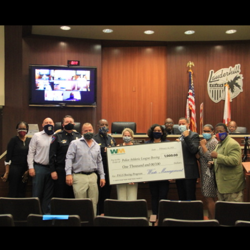 Vice mayor grant alongside others holding a large check in Lauderhill commission chamber