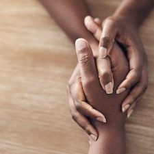 two hands holding a third hand from across a table